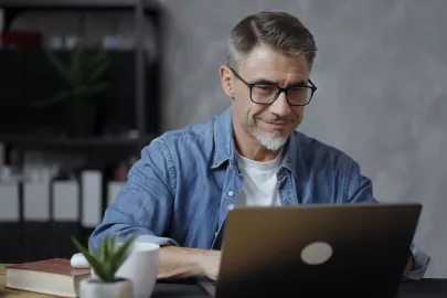 Mann mit Brille arbeitet an einem Laptop